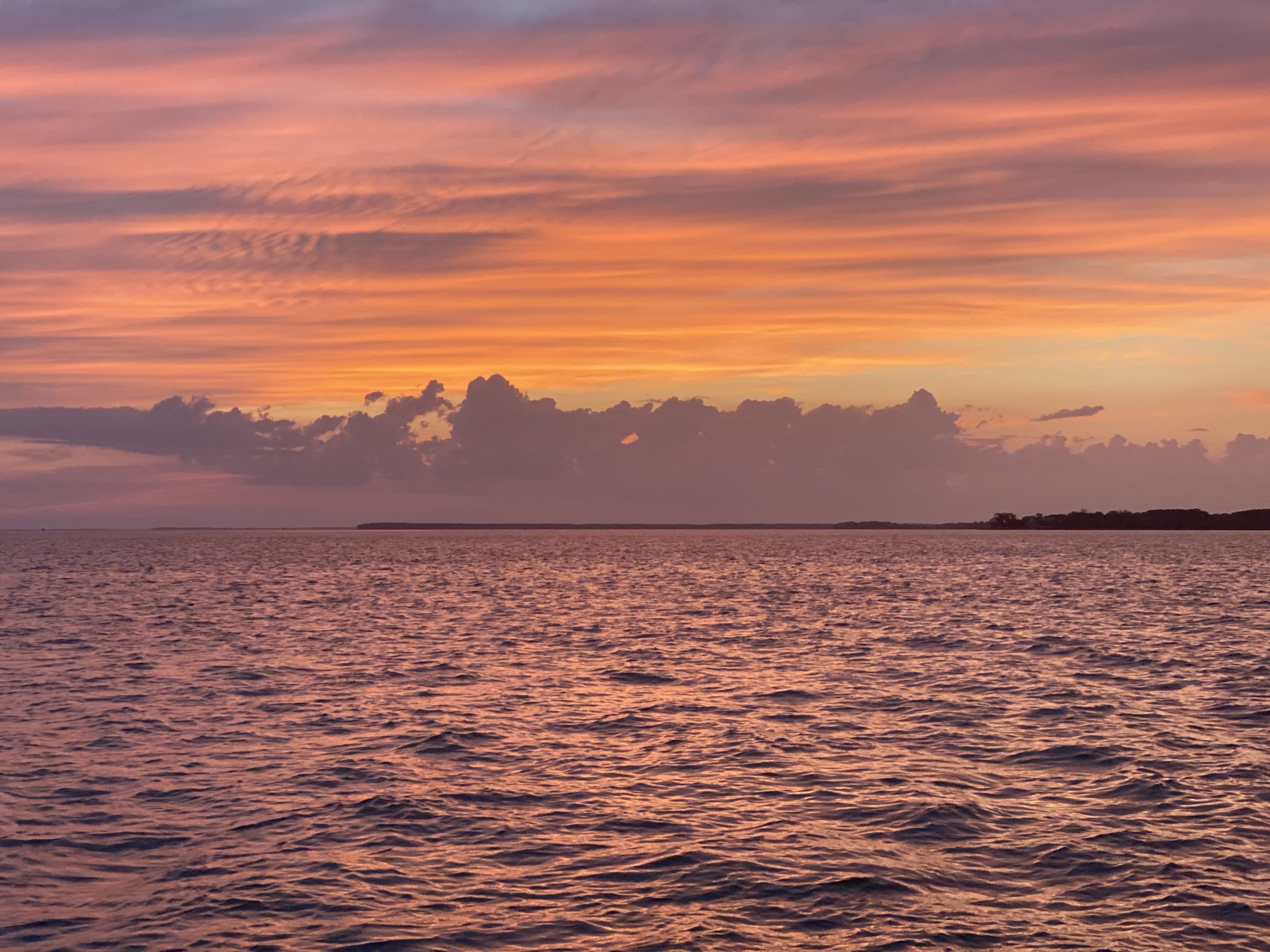 Calm sea with a vibrant sunset, featuring pink and orange skies.